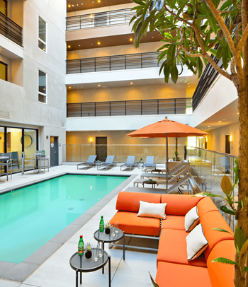 a swimming pool with orange couches and tables
